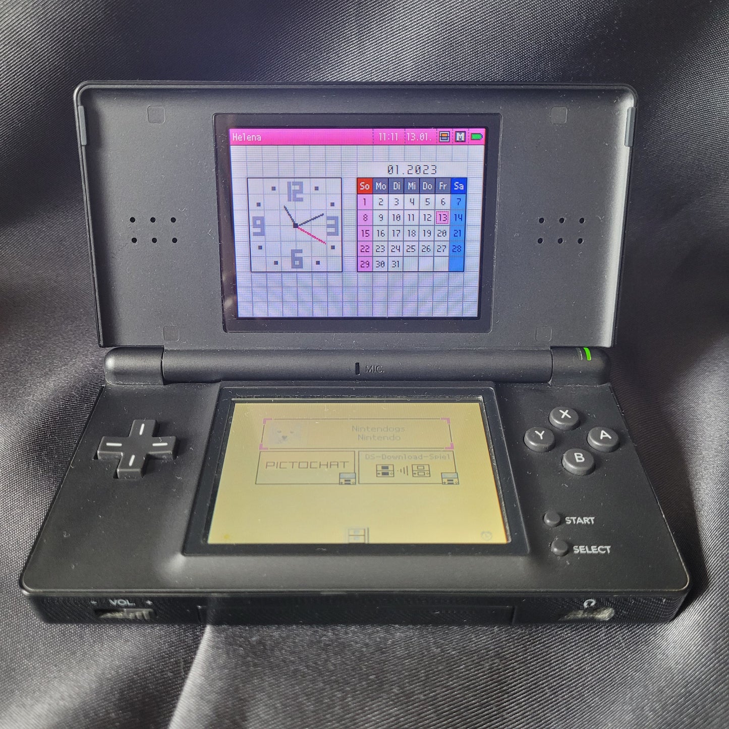 Nintendo DS Lite Konsole Schwarz – Modell USG‑001 – Vintage Handheld mit eingeschalteten Bildschirmen, Touchscreen‑Bedienung und klassischem Steuerkreuz.