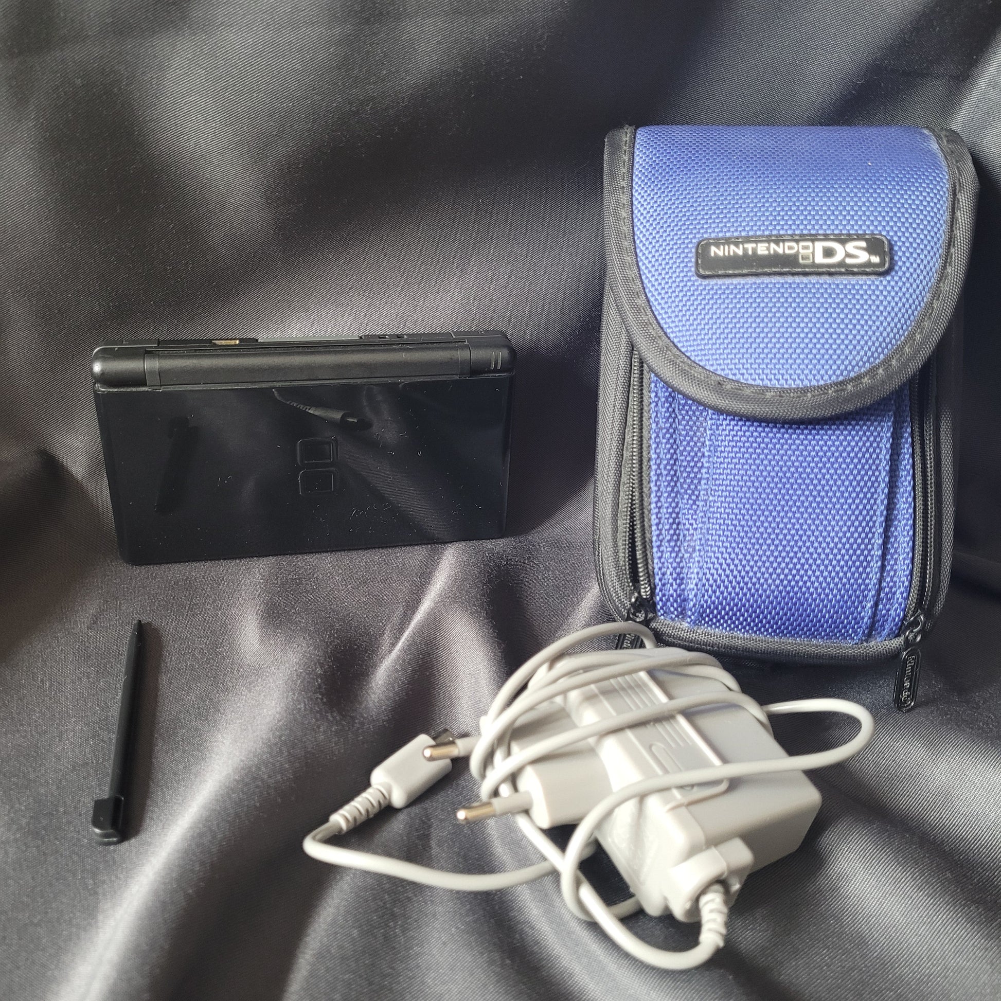 Nintendo DS Lite Konsole Schwarz – Modell USG‑001 – Vintage Handheld mit Stylus, Netzteil und blauer Nintendo‑DS‑Tragetasche für Retro‑Gaming.