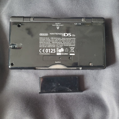 Nintendo DS Lite Konsole Schwarz – Modell USG‑001 – Vintage Handheld, Unterseite mit geöffnetem SLOT‑2‑Schacht für Game‑Boy‑Advance‑Module, technische Angaben und CE‑Kennzeichnung sichtbar.