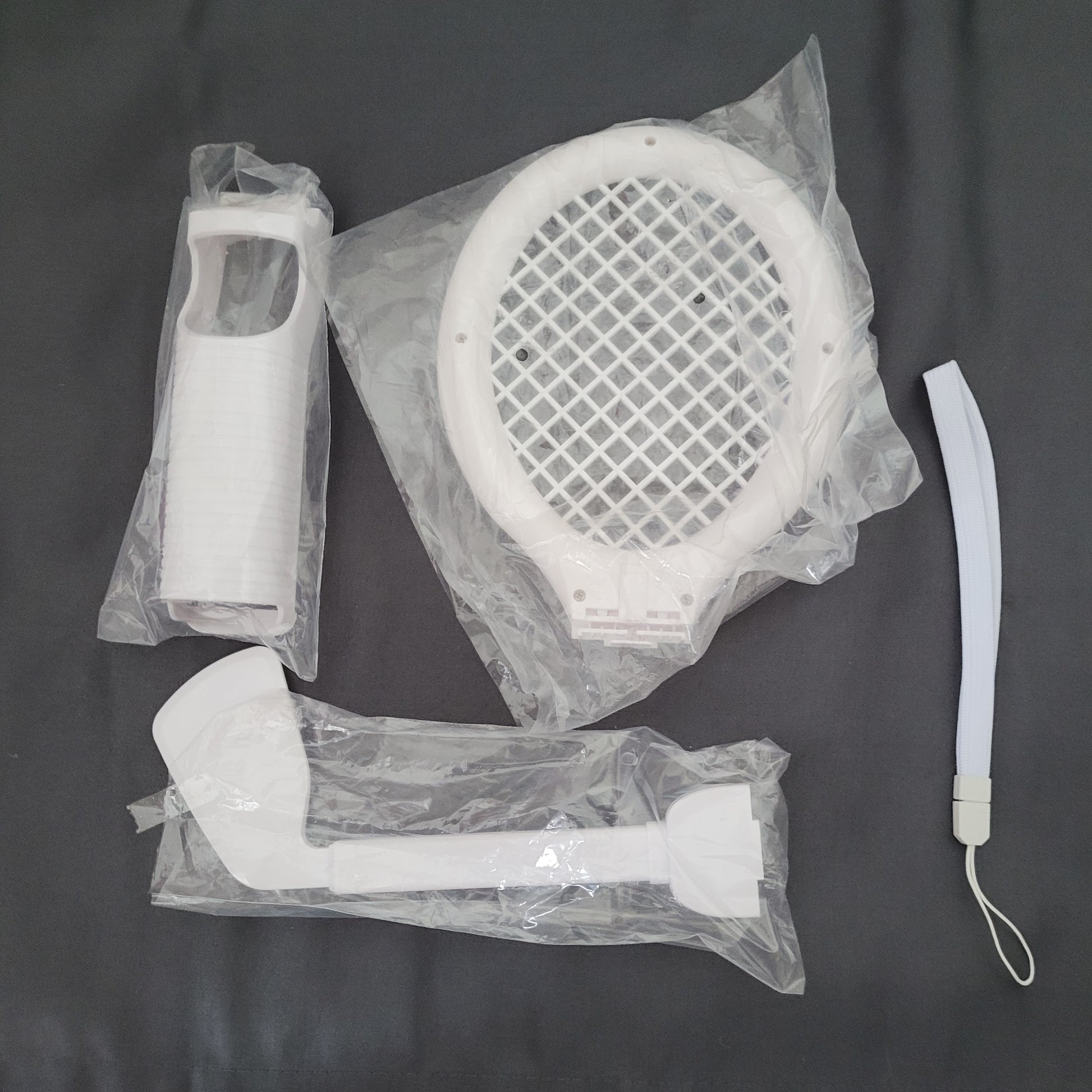 Mehrere Zubehörteile für das Nintendo Wii Sports Pack, darunter ein Tennisracket, ein Baseballschläger und ein Golfschläger als Aufsätze für die Wii-Fernbedienung. Die Zubehörteile sind in einer Verpackung mit der Aufschrift ‚Sports Pack Wii‘ von Watson zu sehen. Die Verpackung weist darauf hin, dass die Wii-Fernbedienung nicht enthalten ist.