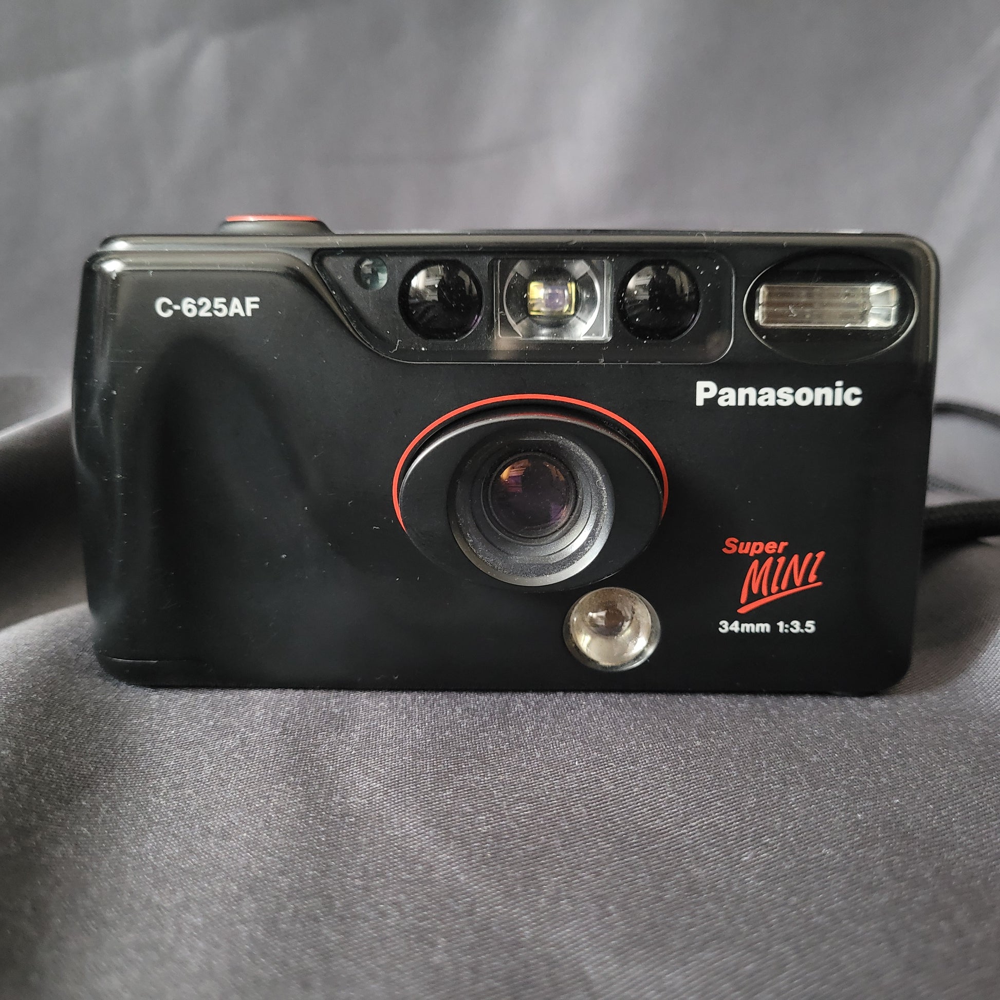 Panasonic Super Mini C-625AF Vintage Analogkamera in Schwarz mit rotem Objektivring, 34mm f/3.5 Linse, Autofokus und eingebautem Blitz – kompakte 35mm Point-and-Shoot Kamera für Sammler klassischer Fototechnik.