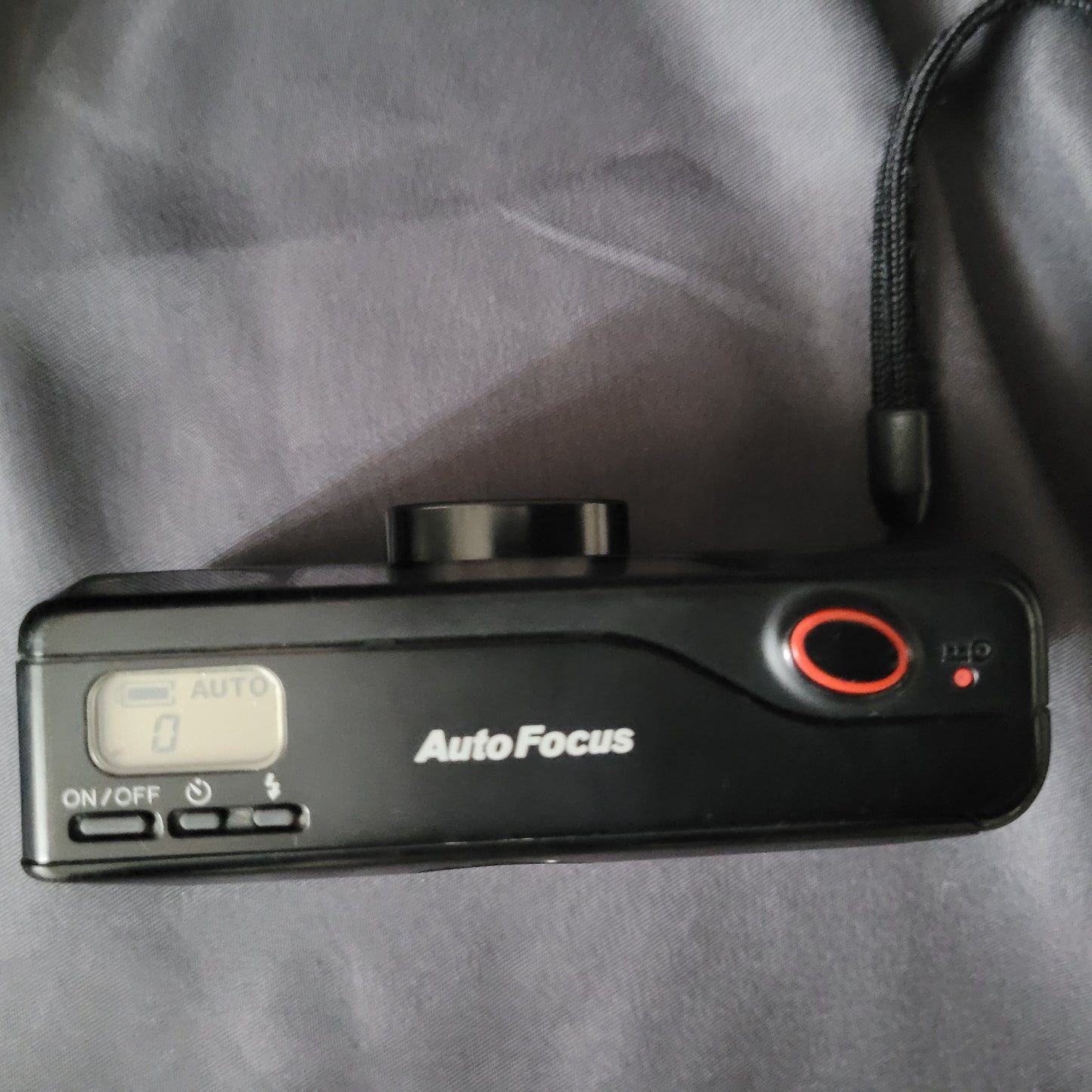 Panasonic Super Mini C-625AF Vintage Analogkamera Draufansicht mit Display, ON/OFF-Taste, rotem Auslöser und Handgelenkschlaufe – kompakte 35mm Autofokus-Kamera für Sammler klassischer Fototechnik.