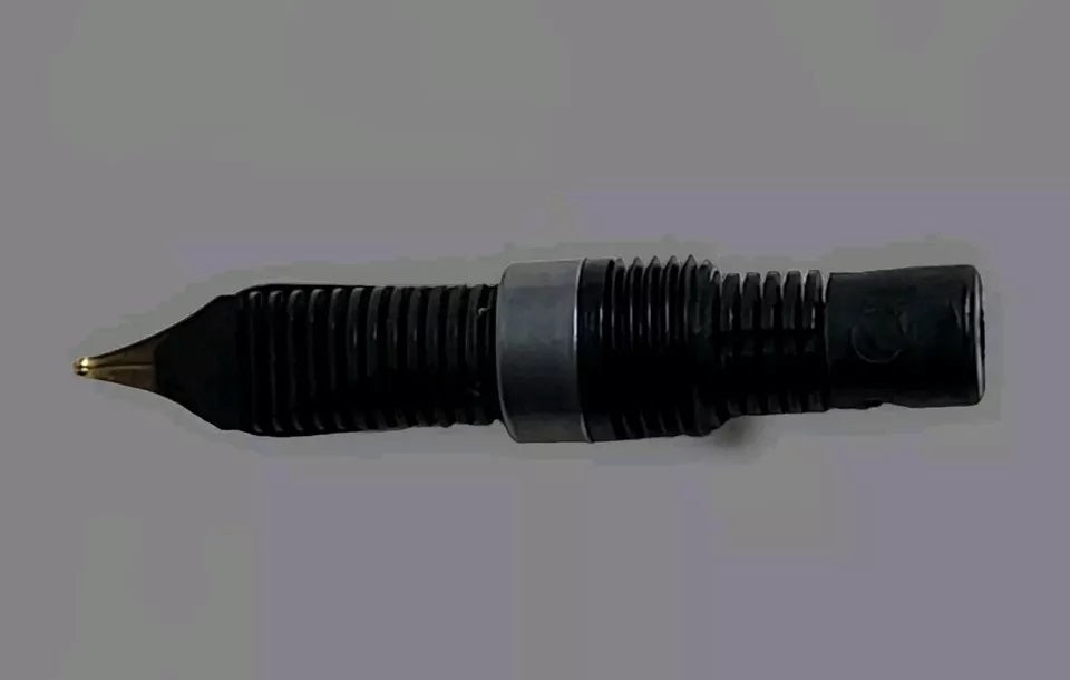 Rückseite der vergoldeten Edelstahlfeder von Pelikan für den M150 (Modelle bis August 1997), Federbreite F, Nahaufnahme auf grauem Hintergrund.