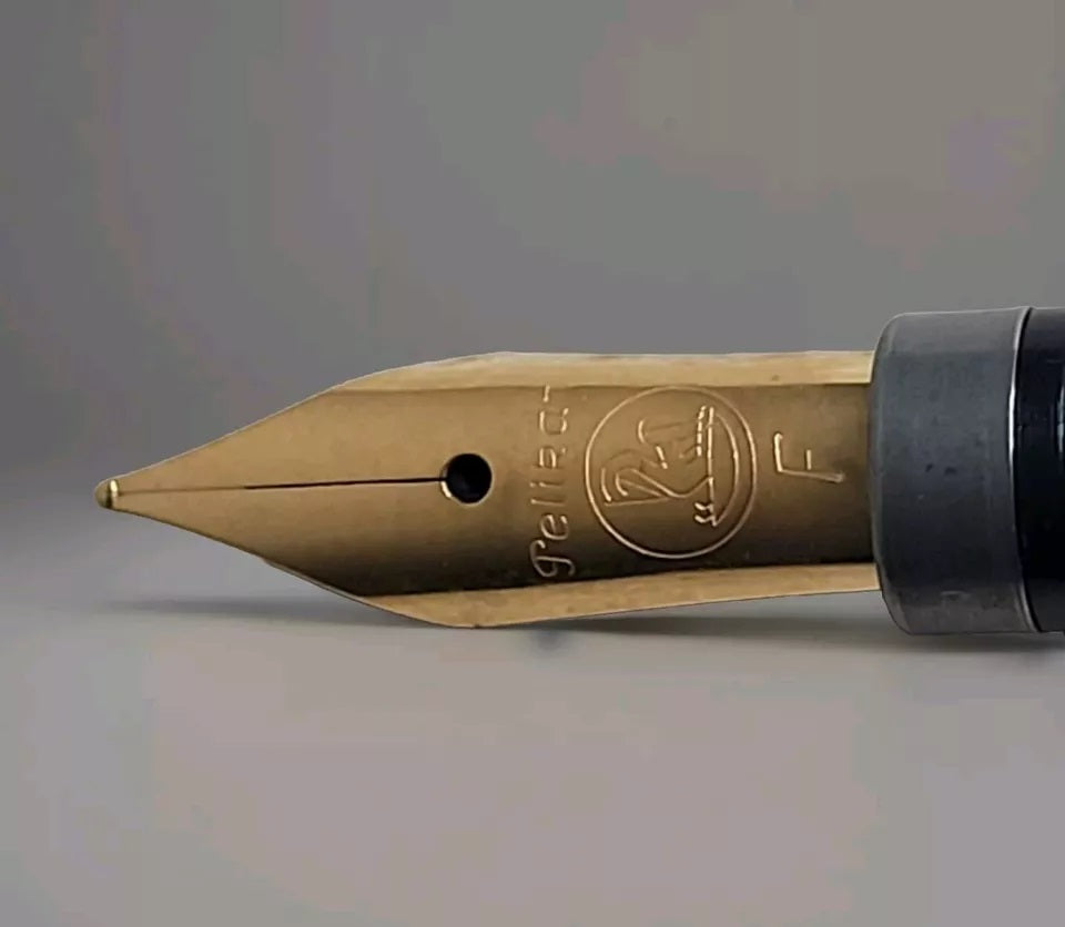 Vergoldete Edelstahlfeder von Pelikan für den M150 (Modelle bis August 1997), Federbreite F, Nahaufnahme auf grauem Hintergrund.