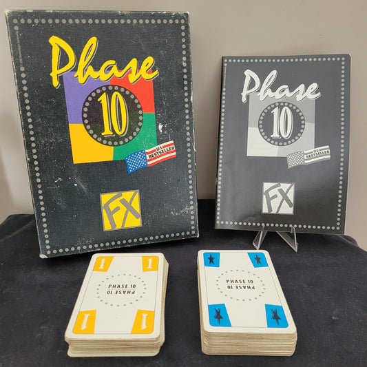 Das originale Phase 10 FX 1998 Ravensburger Vintage Version Gesellschaftsspiel aus Deutschland. Das Bild zeigt das vollständige Spielset mit zwei Stapeln Spielkarten und zwei Anleitungen – eine in Schwarz-Weiß, die andere farbig und mit Gebrauchsspuren. Dieses klassische Ravensburger Gesellschaftsspiel ist ein echtes Vintage-Highlight für Sammler und Liebhaber von Retro-Spielen.
