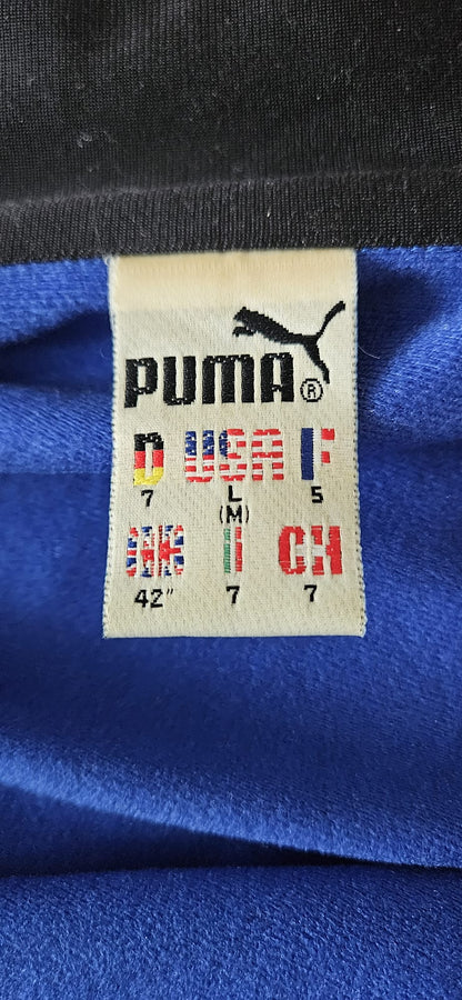 Puma Größenetikett mit internationalen Größenangaben: Deutschland (7), USA (L/M), Frankreich (5), UK (42"), Italien (7), Schweiz (7) – Detailaufnahme des Labels mit Länderflaggen