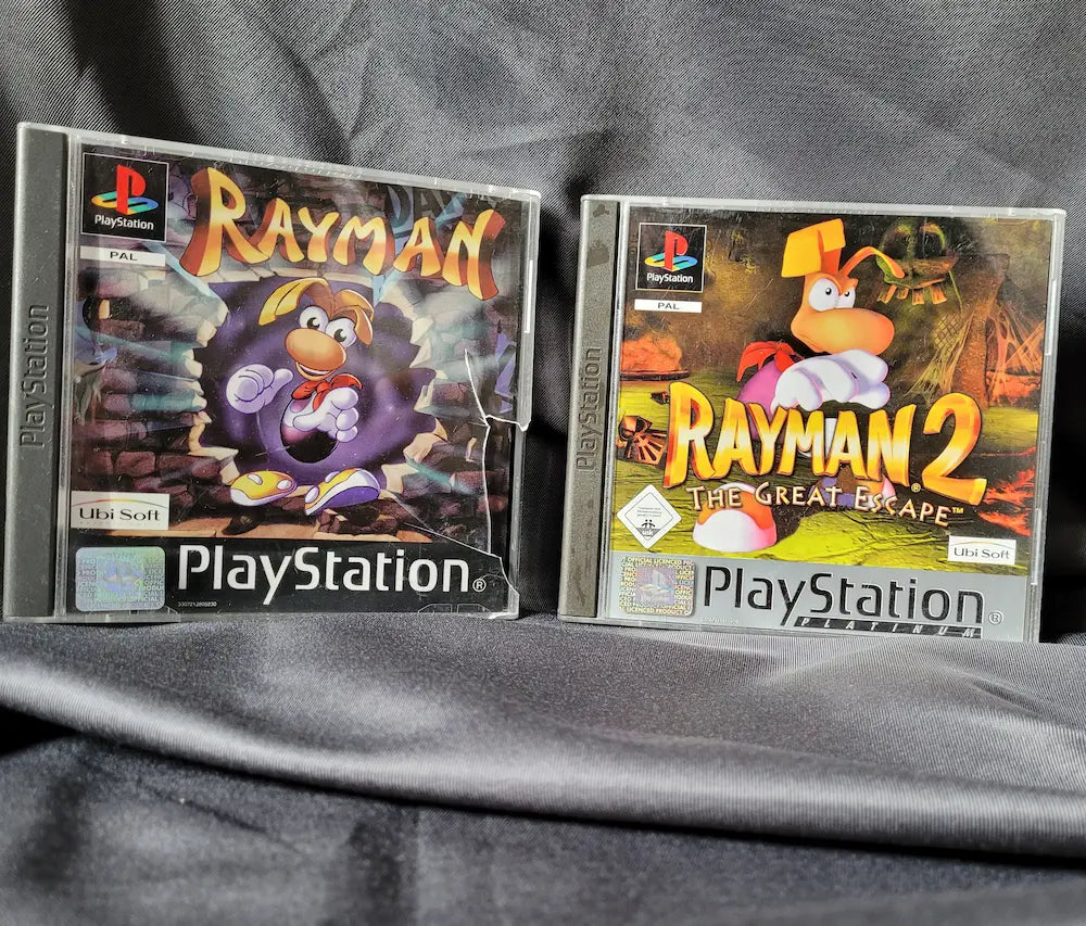 Zwei PlayStation 1 Spiele: Rayman und Rayman 2: The Great Escape inklusive Anleitungen und Discs.