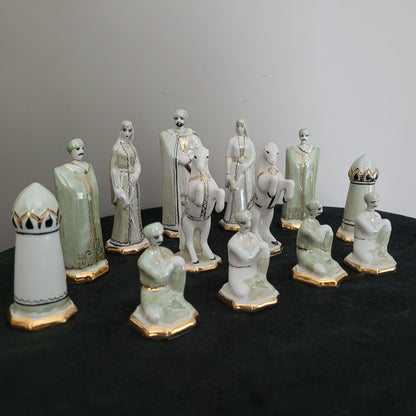 Das Bild zeigt die Vorderseite der Vintage-Schachfiguren aus Kislovodsk, kunstvoll arrangiert auf einem schwarzen Untergrund. Im Hintergrund hebt sich eine weiße Fläche ab, die die feinen Porzellandetails und die Farbgebung der Figuren besonders betont.
