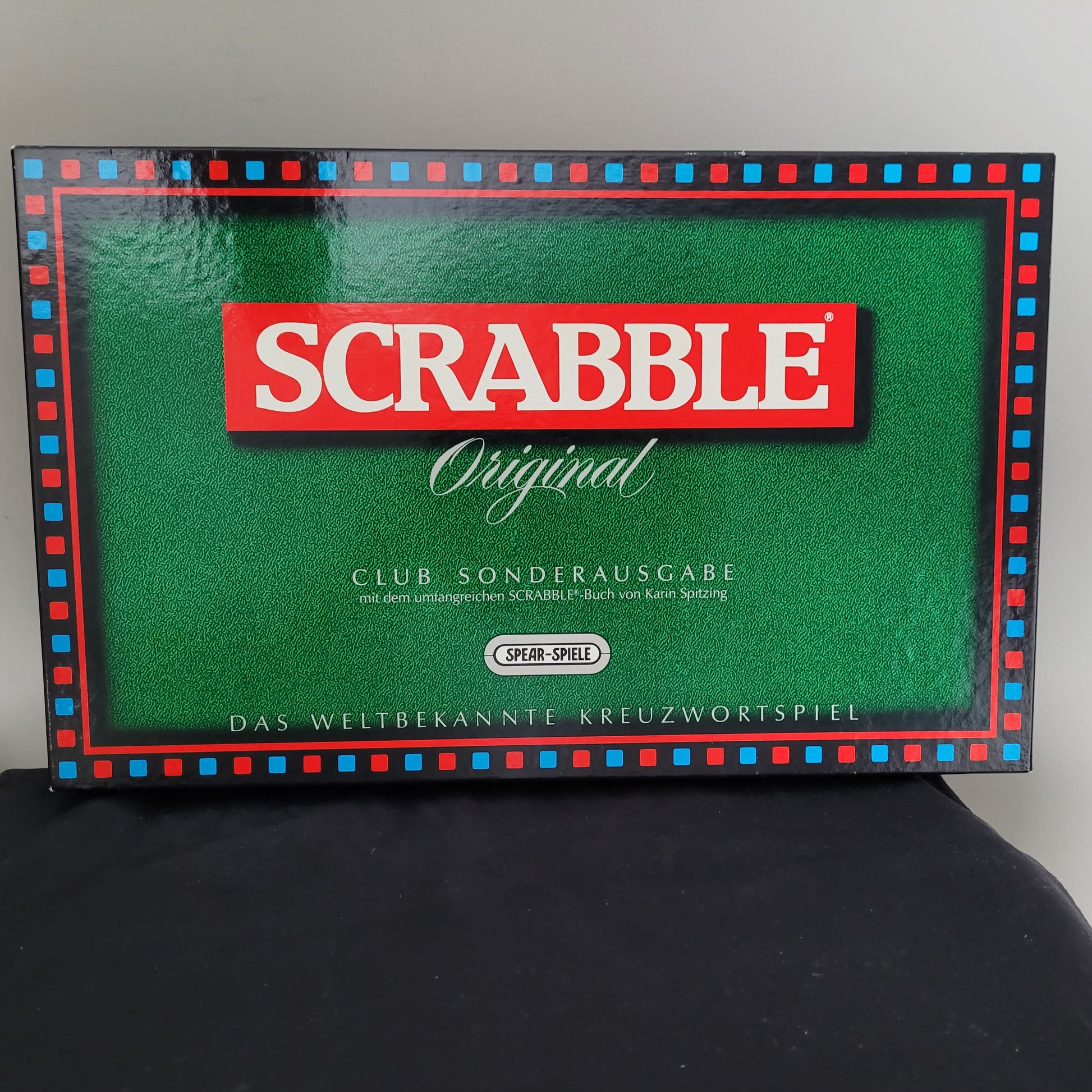 Vorderseite der Scrabble Original Club Sonderausgabe. Grüner Hintergrund mit rotem Scrabble-Logo und der Aufschrift 'Club Sonderausgabe mit Buch von Karin Spitzing'. Sonderausgabe für Fans des Kreuzworträtselspiels.