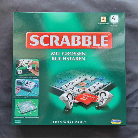 Das Bild zeigt das Scrabble mit großen Buchstaben – ein hochwertiges Gesellschaftsspiel von Piatnik & Mattel, das sich durch seine gut lesbaren Buchstabensteine auszeichnet. Die Verpackung präsentiert das klassische Spielbrett, die extra großen Spielsteine, auf schwarzem Hintergrund.