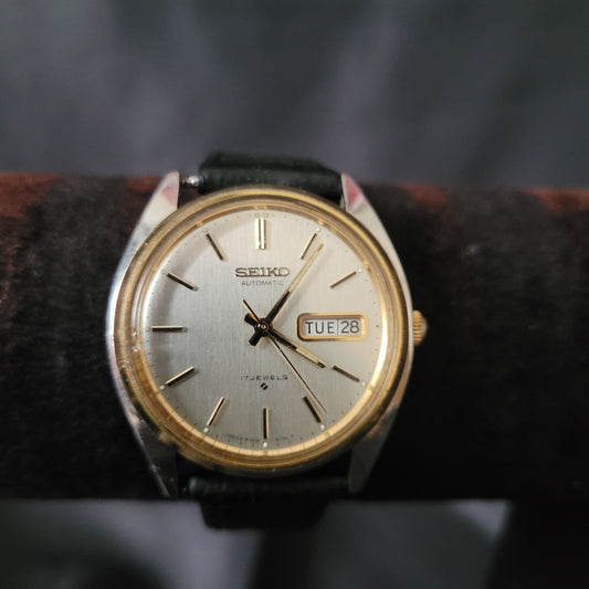 Seiko Automatic Vintage Armbanduhr 6309-8029 aus Japan mit silbernem Zifferblatt, goldfarbenen Indizes und Zeigern, Day-Date-Anzeige bei 3 Uhr sowie schwarzem Lederarmband – klassischer Vintage-Zeitmesser für Sammler.