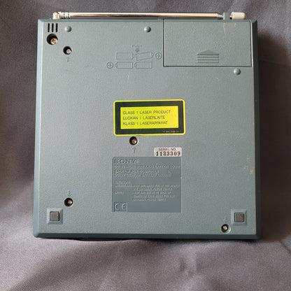 Unterseite vom Sony CD Player – Radio – Wecker ICF‑CD2000S – Vintage: Batteriefachdeckel, seitlicher Antennenstab, mehrere Schrauben, Typenschilder, Laserklasse‑1 Warnhinweis und gut sichtbare Seriennummer auf dunklem Hintergrund.