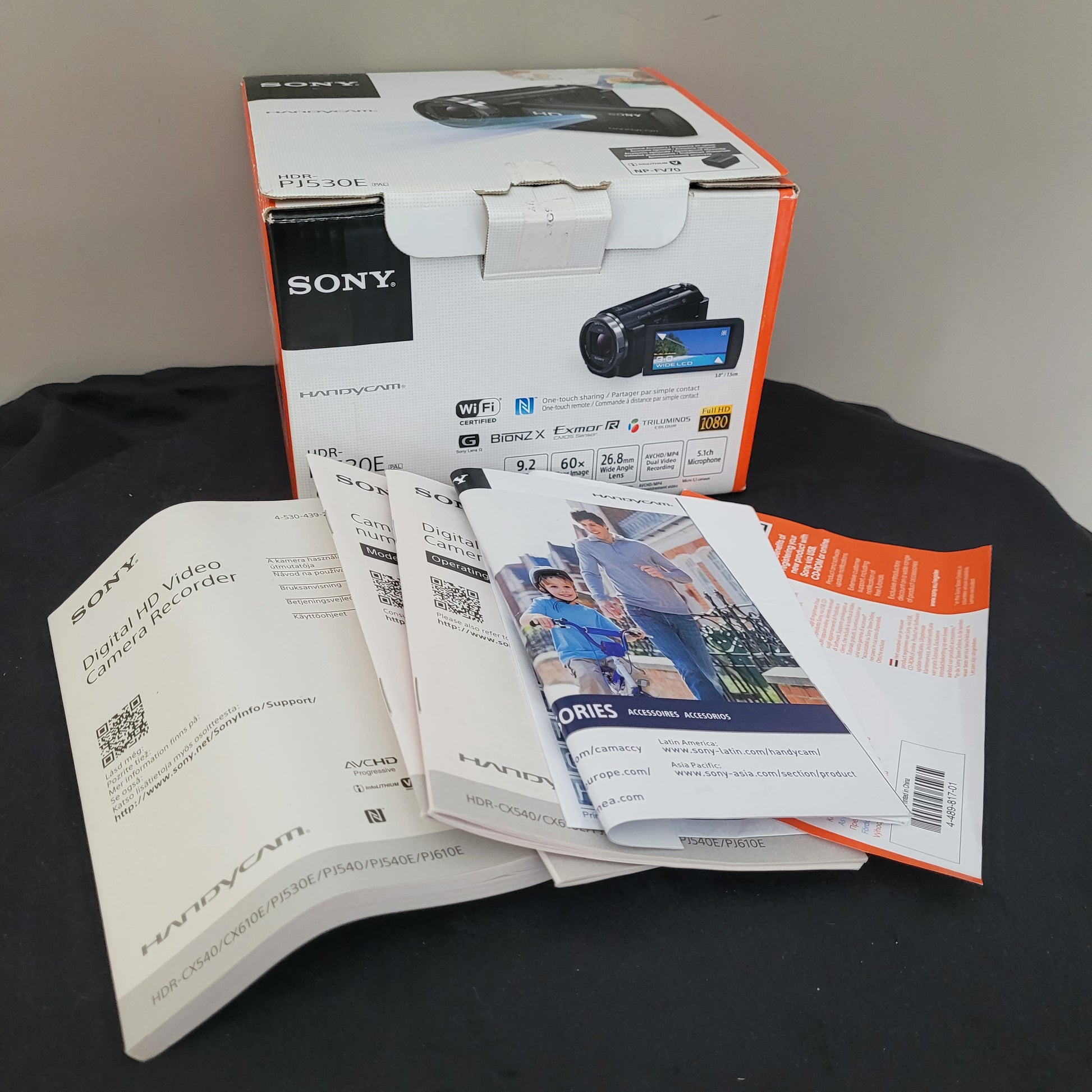 Verpackung der Sony Handycam HDR-PJ530E, abgebildet mit technischen Spezifikationen wie 9,2 MP, HD-Video, WiFi und NFC, sowie beigelegte Bedienungsanleitungen. Perfekt für SEO, da es die Funktionen und die Vielseitigkeit des Camcorders für kreative und technische Nutzer hervorhebt.