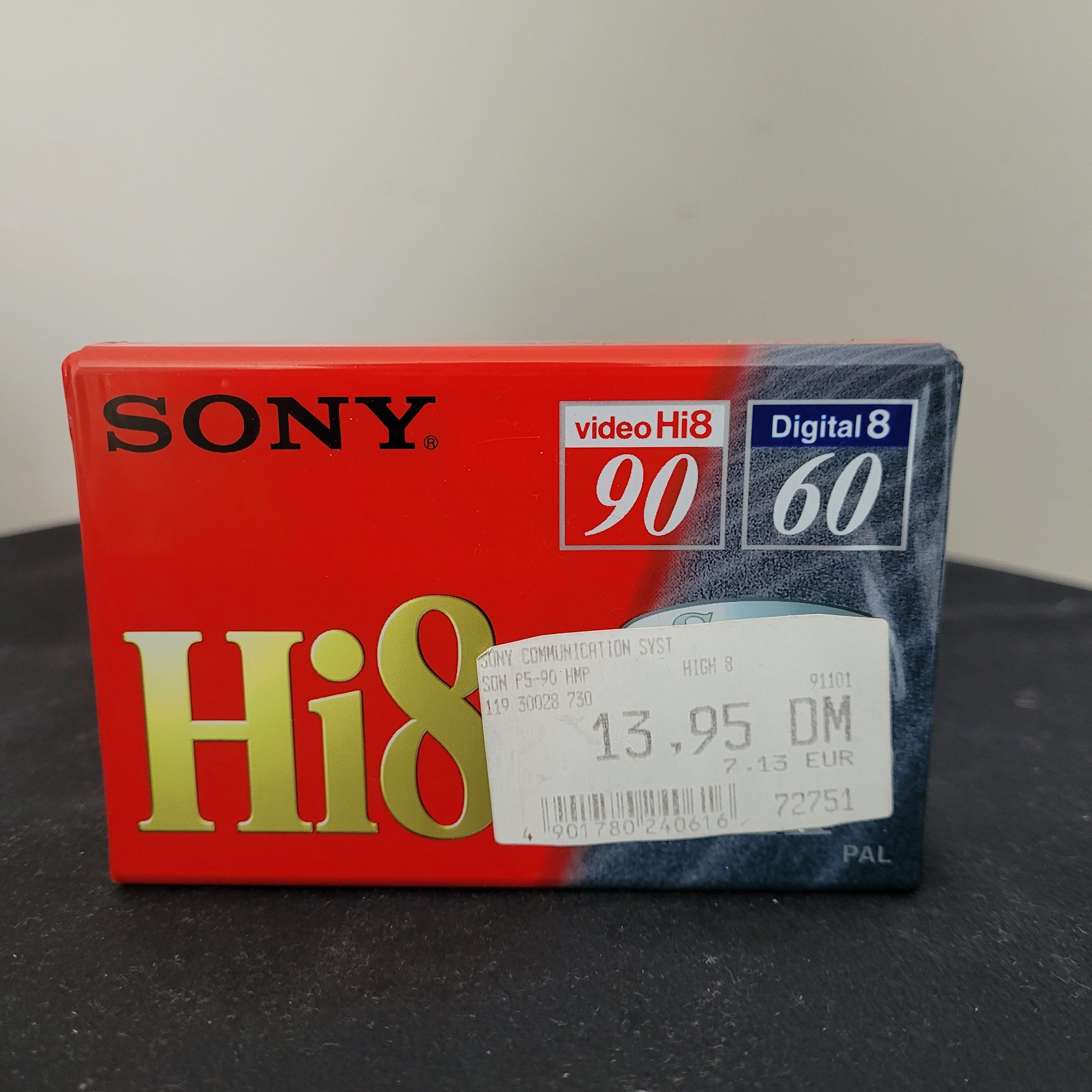 Die Sony Kassette Video Hi8 90 - Digital 8 60 - HMP - PAL - NTSC – P5-90HMP liegt auf dunklem Hintergrund und präsentiert sich im klassischen Vintage-Design. Die Verpackung zeigt technische Spezifikationen wie die Aufnahmekapazität für Hi8 (90 Minuten) und Digital8 (60 Minuten). Das Sony-Logo sowie die Modellbezeichnung P5-90HMP sind deutlich zu erkennen. Ein begehrtes Sammlerstück für Liebhaber analoger Videotechnik und Vintage-Kassetten.