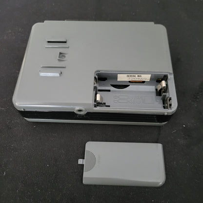 Rückansicht eines geöffneten Sony Walkman WM-B12 Kassettenspielers in graugrünem Gehäuse mit freiliegendem Batteriefach, sichtbaren Metallkontakten und eingeprägten Polaritätssymbolen zur korrekten Batterieausrichtung; rechts daneben liegt die abgenommene Batteriefachabdeckung. Im Inneren befindet sich ein Etikett mit der Seriennummer "SERIAL NO. 3204604". Das Gerät zeigt Schrauböffnungen und Befestigungsschlitze – ideal für Technikliebhaber und Sammler von Vintage-Audioelektronik.