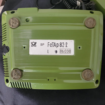 Die Unterseite des Post FetAp 82-2 mit Schlüssel Vintage-Tastentelefons aus den 80er Jahren auf dunklem Hintergrund. Sichtbar sind technische Details wie die Anschlussbuchsen, Kabelführung und Seriennummer. Die solide Verarbeitung und die robuste Bauweise unterstreichen das klassische Design dieses ikonischen Retro-Telefons – ein Stück Telekommunikationsgeschichte mit originaler Technik.