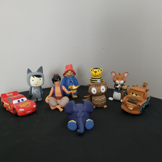 Neun gebrauchte Tonie Figuren auf schwarzem Hintergrund, darunter Paddington Bär, Leo Lausemaus, Die Eule mit der Beule, Aladdin, Disney Cars MC Queen & Hook. Perfekt für Toniebox-Fans.