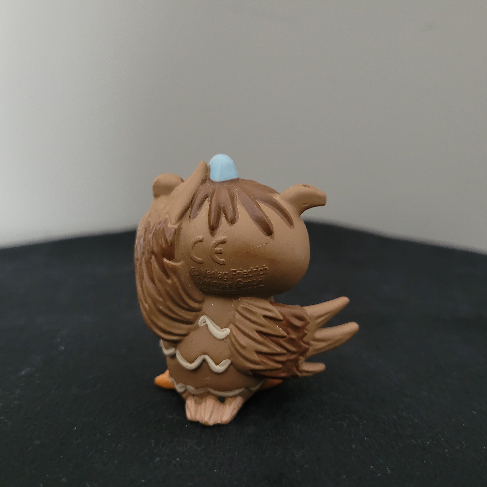 Tonie / Tonies Figur die Eule mit der Beule. Zu sehen ist die Rückseite auf schwarzer Oberfläche und grauem Hintergrund.