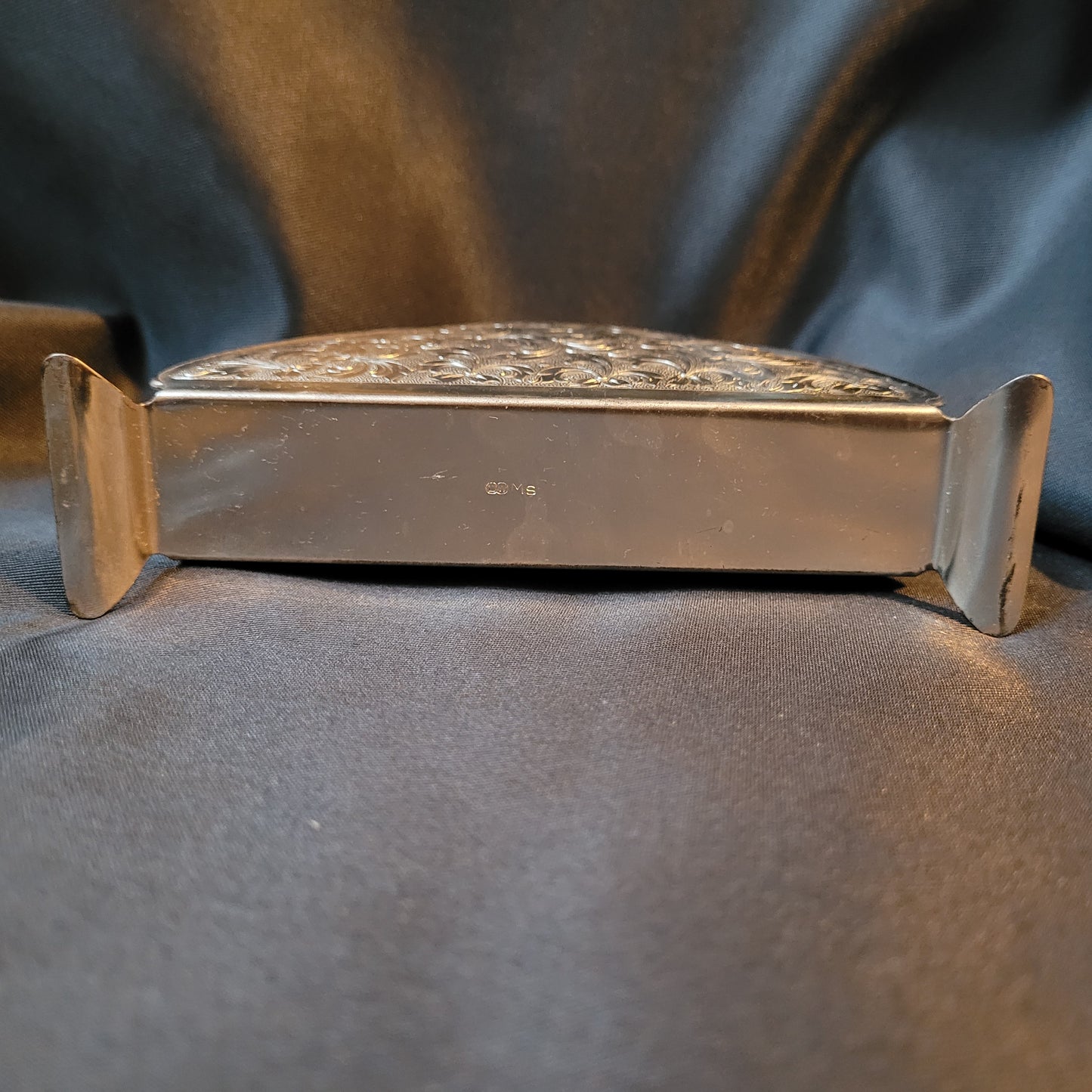 Versilberter Serviettenhalter Vintage, silberfarben, Unterseite mit Punze L und W in Kreisen, daneben großes M und kleines s, schwarzer Hintergrund.