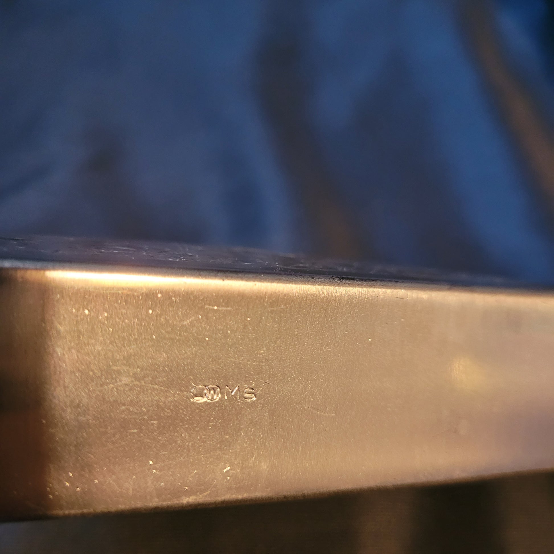 Versilberter Serviettenhalter Vintage, silberfarben, Unterseite mit Punze L und W in Kreisen, daneben großes M und kleines s, schwarzer Hintergrund.