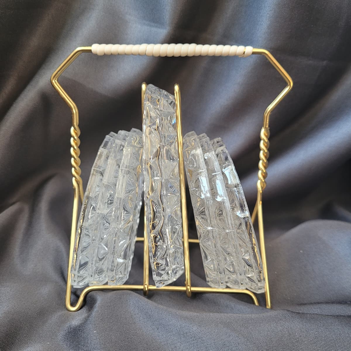 Vintage - Mid-Century 7-teiliges Set aus gepressten Bleikristall-Untersetzern in einem goldfarbenen Metallhalter.