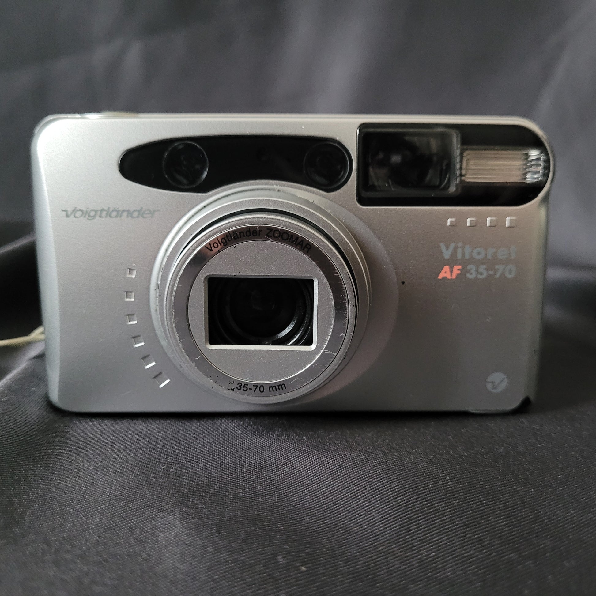 Voigtländer Vito AF 35-70 Vintage Analogkamera in Silber mit Voigtländer Zoomar 35–70mm f/5.6 Objektiv, eingebautem Blitz und Autofokus – klassische 35mm Kompaktkamera für Sammler und Liebhaber analoger Fototechnik.