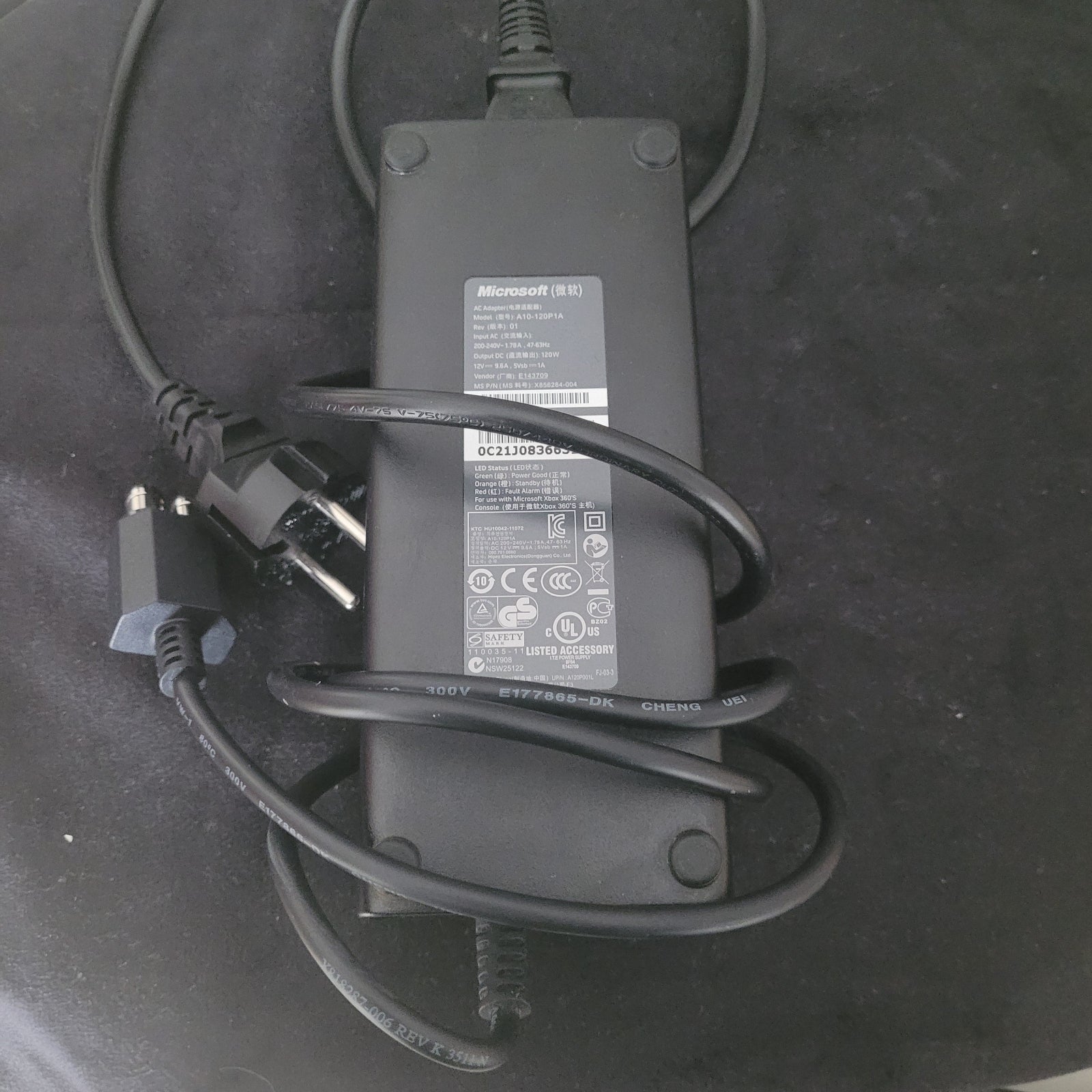 Zu sehen ist das Netzteil passend zum Produkt Xbox 360 S Modell 1439, auf schwarzem Unter- und weißem Hintergrund.