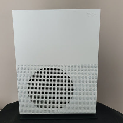 Das Foto zeigt die Seitenansicht einer weißen Xbox One S Konsole in vertikaler Position. Erkennbar ist das charakteristische große, runde Lüftungsgitter mit Wabenstruktur auf der rechten Geräteseite, während das dezente Xbox-Logo links oben eingelassen ist.
