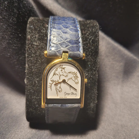 Elegante Alpina Georges Claude Armbanduhr mit drei Pferdeköpfen auf dem weißen Zifferblatt, goldenem Gehäuse und blauem Lederarmband.