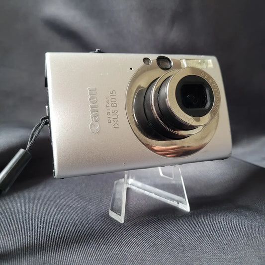 Silberne Canon Digital IXUS 80 IS Kompaktkamera auf einem transparenten Standfuß.