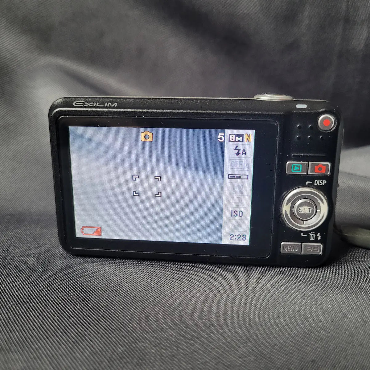 Schwarze Casio Exilim Kompaktkamera mit 8.1 Megapixeln und 3-fach optischem Zoom. Rückseite.