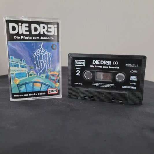 Schwarze Hörspielkassette und Hülle von Die Dr3i – Folge 2: Die Pforte zum Jenseits aus der Rocky Beach Serie.
