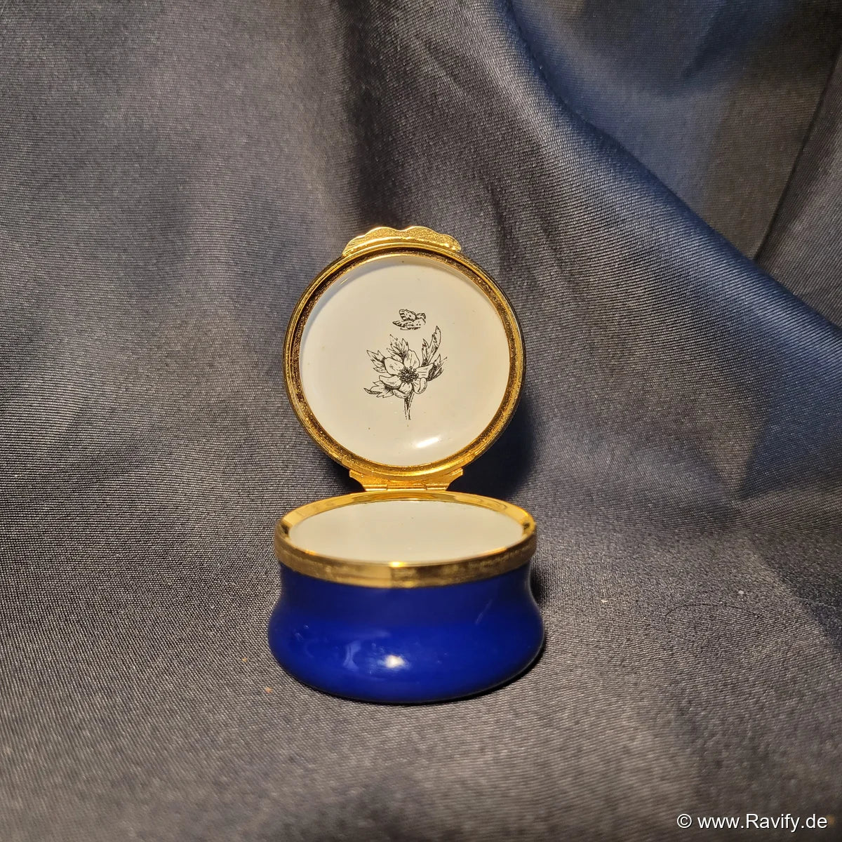 Klassische, runde Halcyon Days Enamels Pillendose in Kobaltblau mit handgemaltem Blumenmotiv auf dem Deckel und feuervergoldeter Fassung.