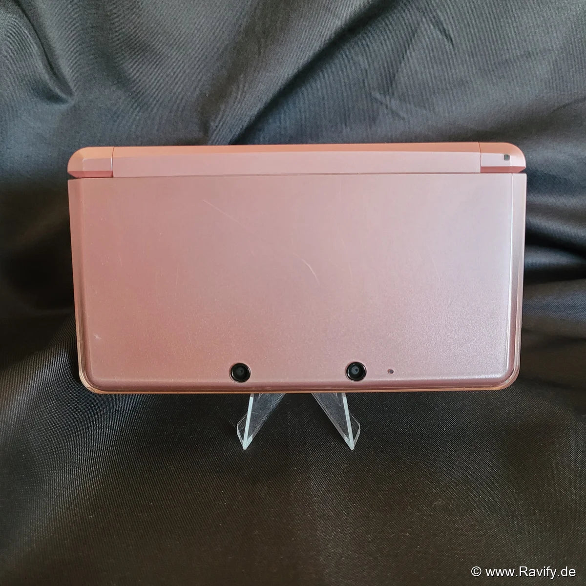 Nintendo 3DS XL Konsole in Pink und Rosa auf Stoffhintergrund.