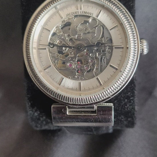 Video-Faszination Mechanik: Jacques Lemans Automatik 1-1212 Skelett-Herrenuhr mit poliertem Edelstahlgehäuse und transparentem Einblick in das Uhrwerk.