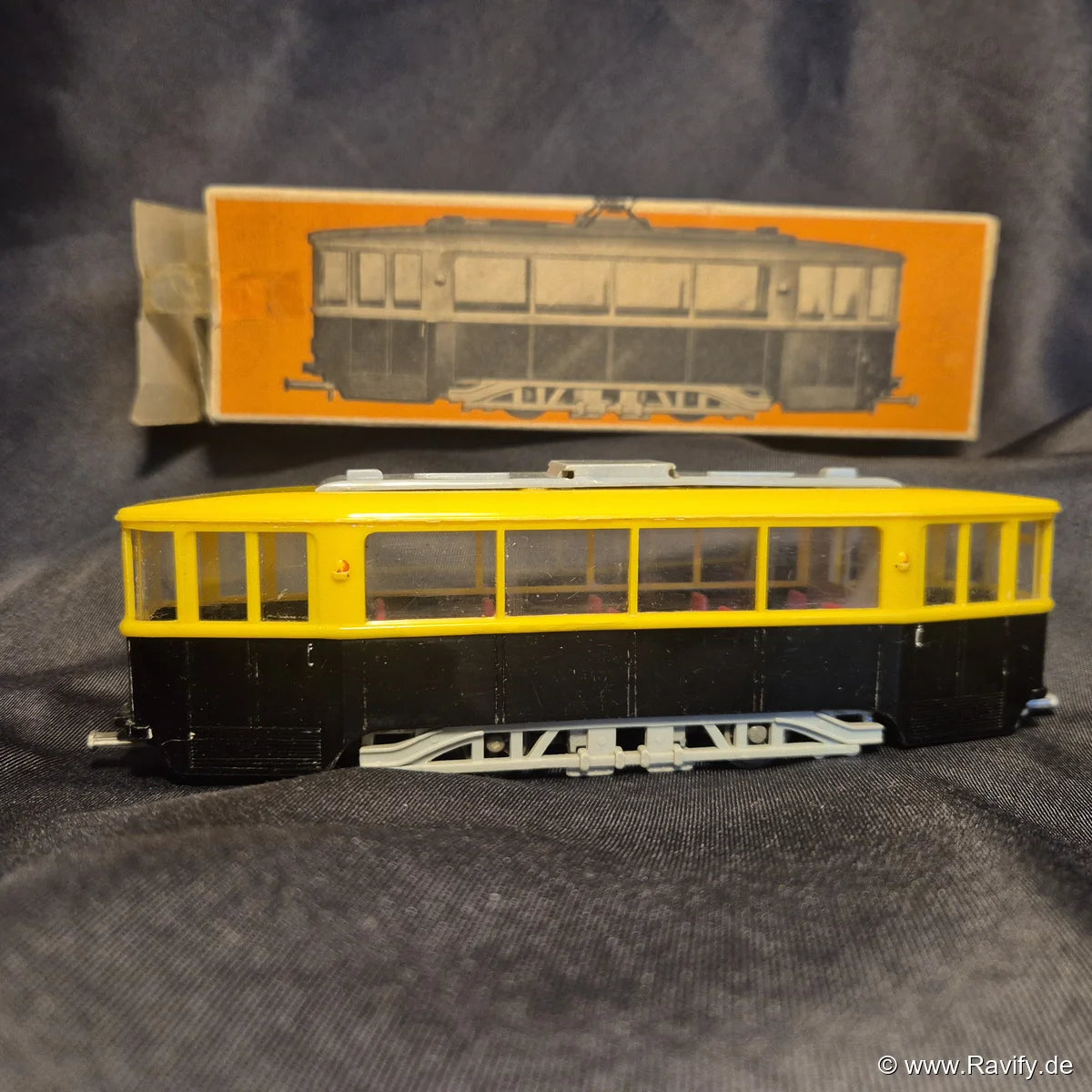 Siku V-Serie V40 Straßenbahn im Maßstab 1:60 in Gelb/Schwarz mit Originalverpackung im Hintergrund