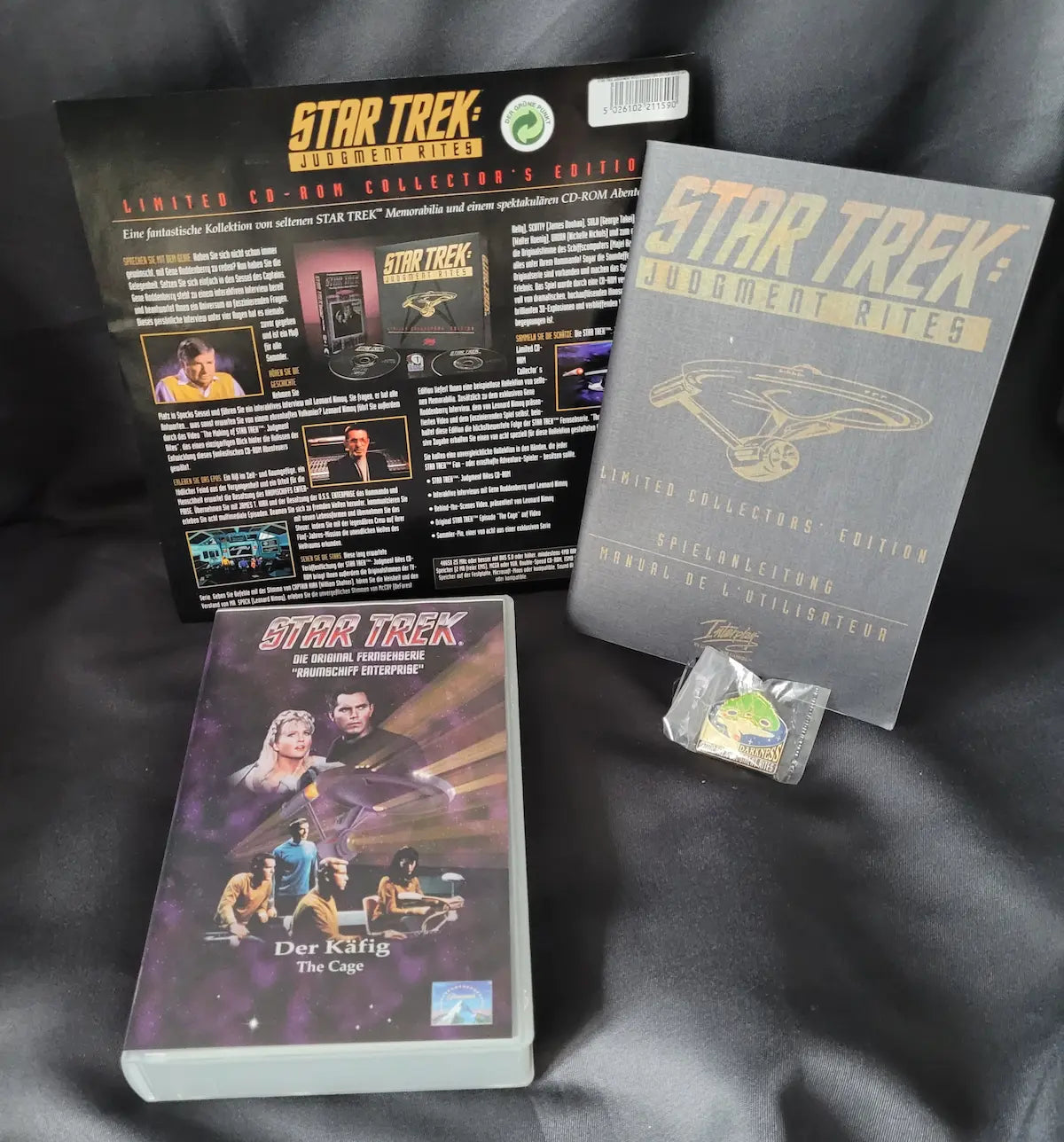 Lieferumfang der Star Trek: Judgment Rites Limited Collector's Edition mit Spielanleitung, VHS-Kassette "Der Käfig" und Sammler-Pin.
