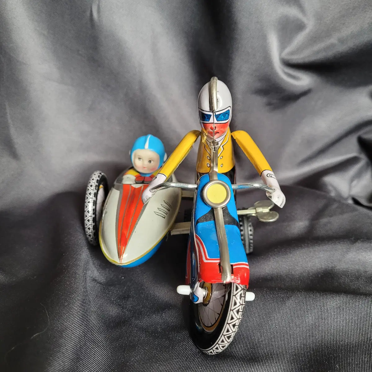 Klassisches Blechspielzeug-Motorradgespann in Grün mit Beiwagen und detaillierter lithografierter Fahrerfigur im Vintage / Retro-Look.
