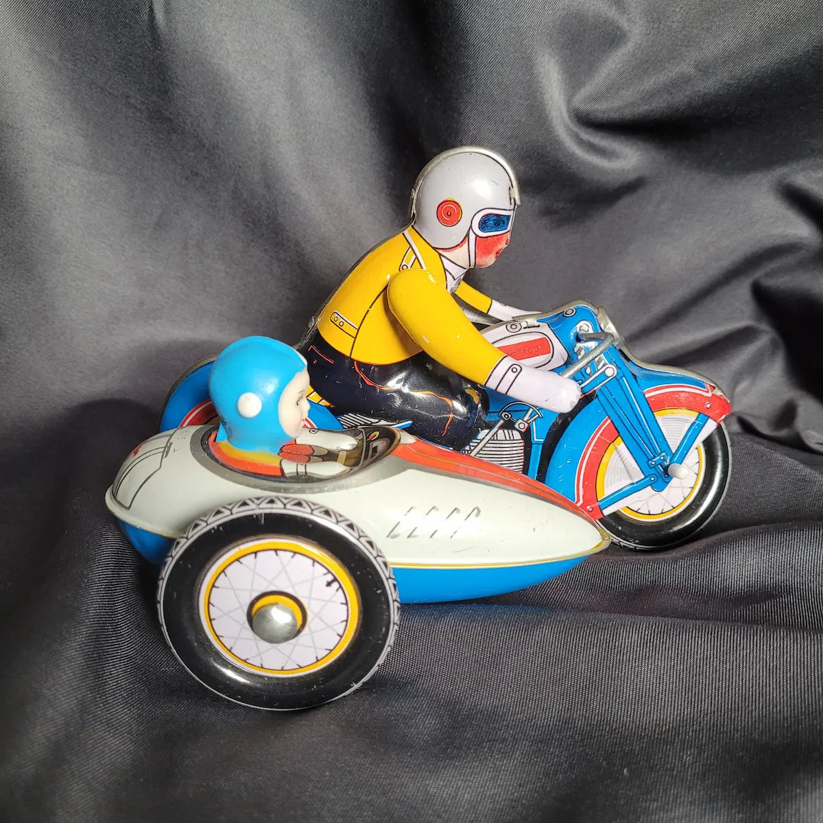 Klassisches Blechspielzeug-Motorradgespann in Grün mit Beiwagen und detaillierter lithografierter Fahrerfigur im Vintage / Retro-Look.
