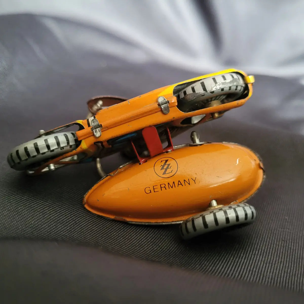 Klassisches, orange-gelbes Miniatur-Blechspielzeug Motorradgespann mit Beiwagen und dem Logo ZZ Germany auf der Unterseite.