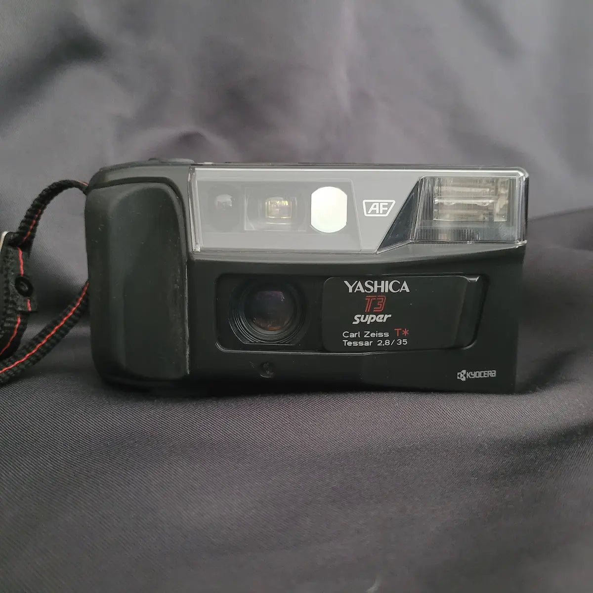 Vorderansicht der schwarzen Yashica T3 Super Point-and-Shoot Analogkamera mit sichtbarem Carl Zeiss Tessar Objektiv.